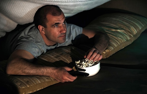 homme regardant un film à la maison sur le canapé la nuit