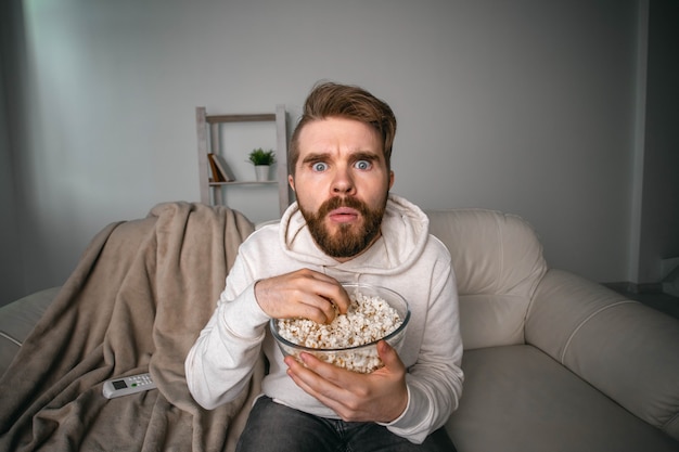 Homme regardant des films assis sur un canapé à la maison