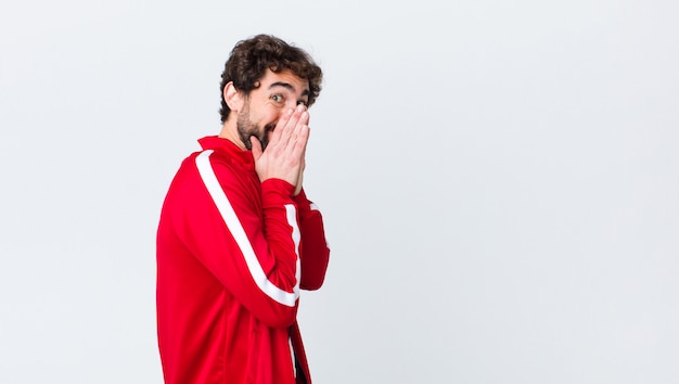 homme regardant heureux, gai, chanceux et surpris couvrant la bouche avec les deux mains