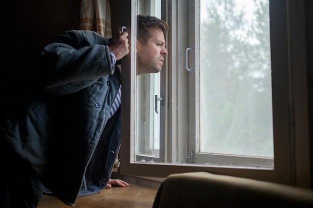 Homme regardant par la fenêtre pendant la quarantaine de covid 2019 Concept d'espionnage des voisins