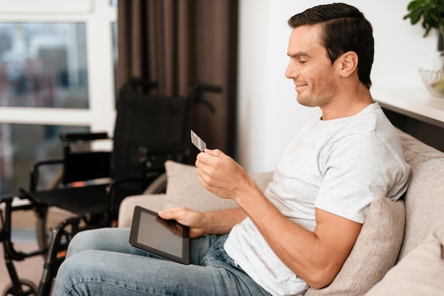 Un homme regarde une carte de crédit et entre des données dans la tablette.