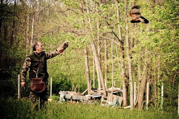 Photo un homme regarde un oiseau dans la forêt.