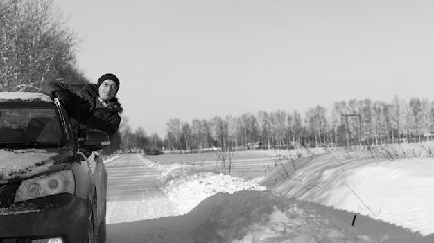 L'homme regarde par la fenêtre de la voiture la route enneigée et souriant