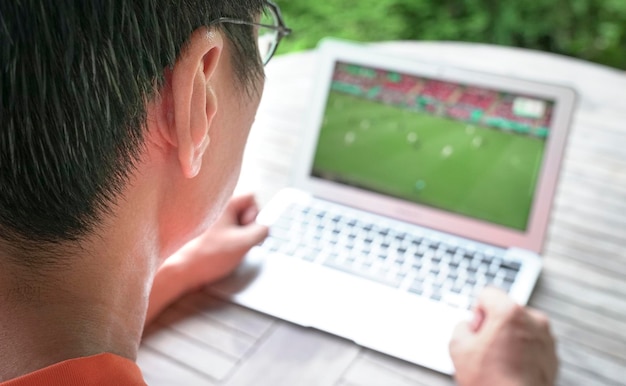 L'homme regarde le sport de football sur un ordinateur portable