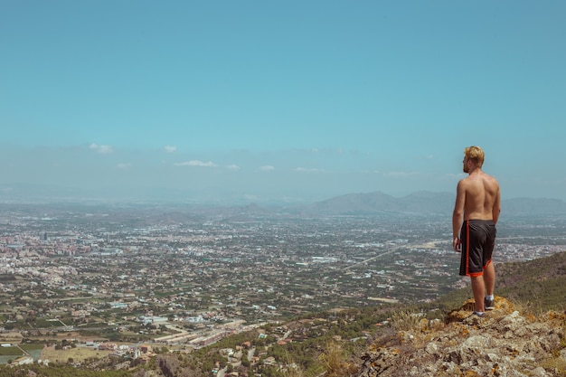 Un homme regarde la ville du bord de la falaise