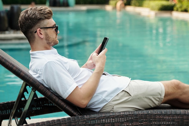 Homme relaxant au bord de la piscine