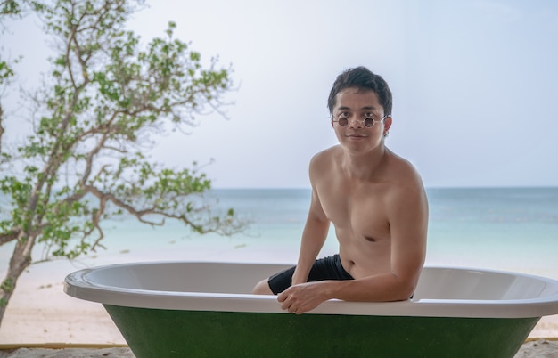 Homme relaxant dans la baignoire avec fond océan plage.