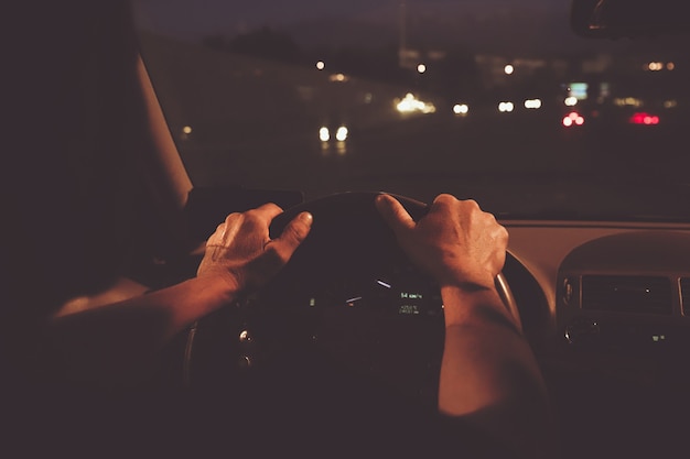 L'homme Remet Le Conducteur Au Volant D'une Voiture Moderne Avec Tableau De Bord De Voiture Et Fond De Ville De Nuit