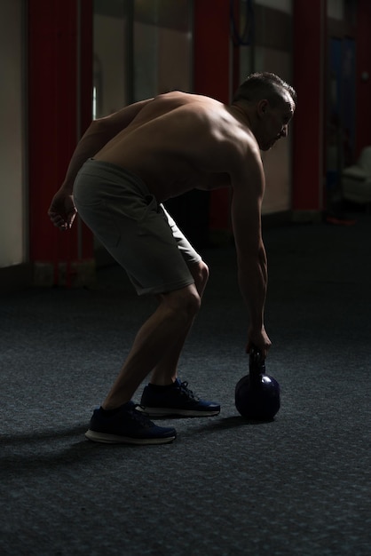 Homme de remise en forme à l'aide de kettlebells à l'intérieur de la salle de sport