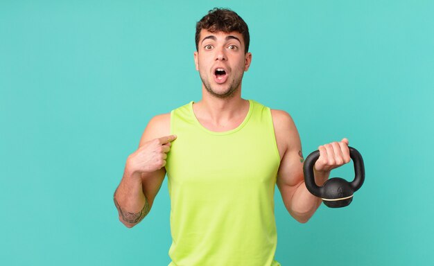 Homme de remise en forme ayant l'air choqué et surpris avec la bouche grande ouverte, pointant vers soi