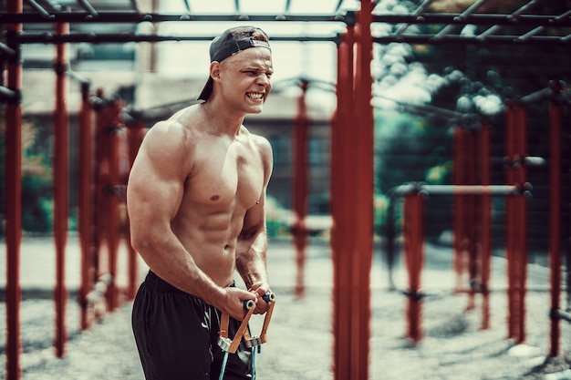 Homme de remise en forme avec bande d'étirement dans la salle de sport en plein air