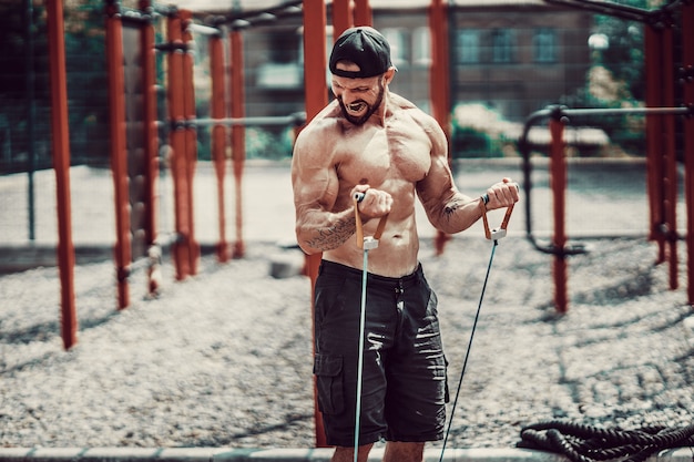 Homme de remise en forme avec bande d'étirement dans la salle de sport en plein air