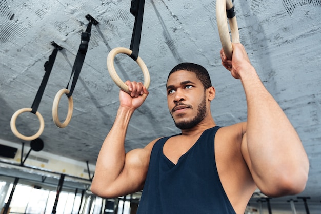 Homme de remise en forme faisant des exercices de trempage à l'aide d'anneaux dans la salle de sport