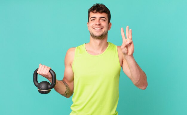 Homme de remise en forme souriant et à l'air sympathique, montrant le numéro trois ou troisième avec la main vers l'avant, compte à rebours