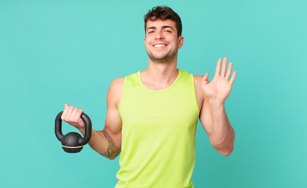 Homme de remise en forme souriant joyeusement et joyeusement, agitant la main, vous accueillant et vous saluant, ou vous disant au revoir