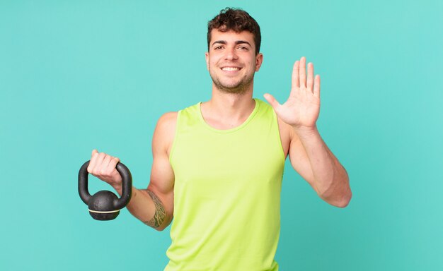 Homme de remise en forme souriant et semblant amical, montrant le numéro cinq ou cinquième avec la main vers l'avant, compte à rebours