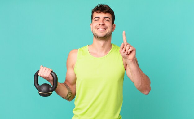 Homme de remise en forme souriant et semblant amical, montrant le numéro un ou le premier avec la main en avant, compte à rebours