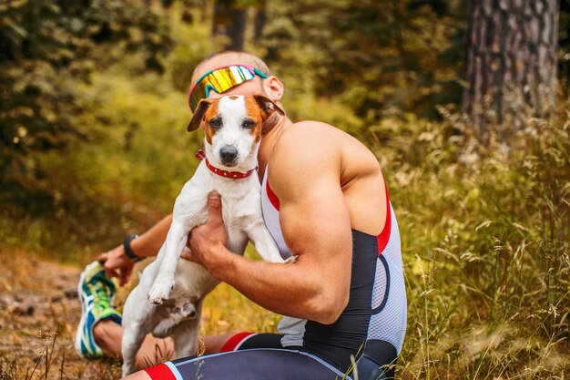 Homme de remise en forme en vêtements de sport avec son chien dans la forêt.