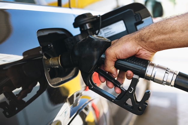 Homme remplissant le carburant d'essence dans la voiture à la station service