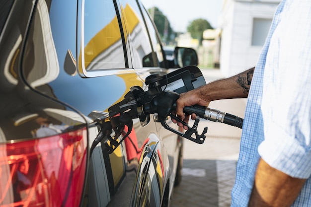 Homme remplissant le carburant d'essence dans la voiture à la station service