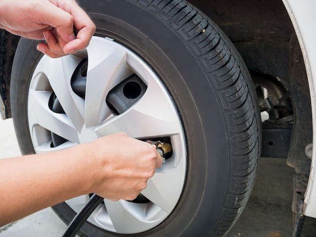 Homme remplissant la pression d'air dans le pneu de voiture se bouchent