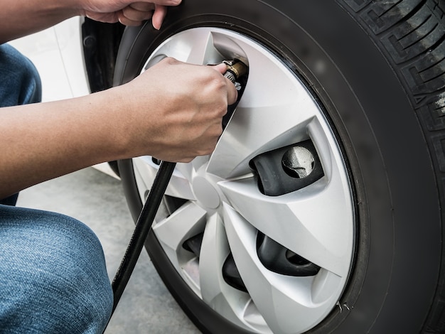 Homme remplissant la pression d'air dans le pneu de voiture