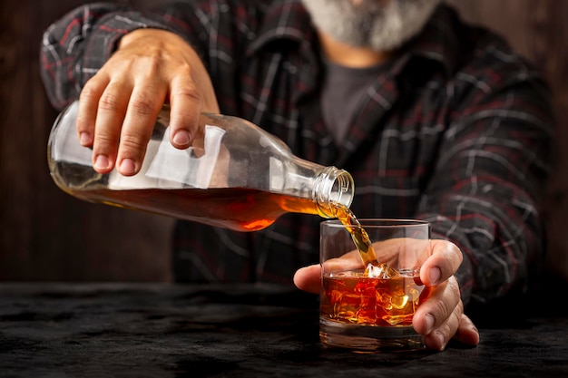 Homme remplissant un verre de whisky