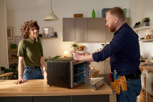 Homme réparant un micro-ondes cassé à la maison