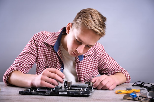 Homme réparant un ordinateur cassé, une carte vidéo, une mémoire RAM, un refroidisseur, un processeur, un disque dur.Jeune réparateur travaillant avec un tournevis dans un centre de service.