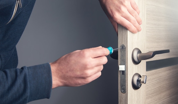 Homme réparant la poignée de porte avec un tournevis