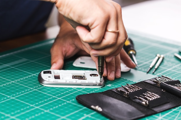 Homme Réparant Un Smartphone Cassé, Photo En Gros Plan.