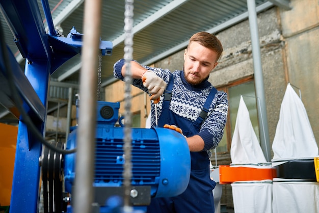 Homme réparant des unités de machine en usine