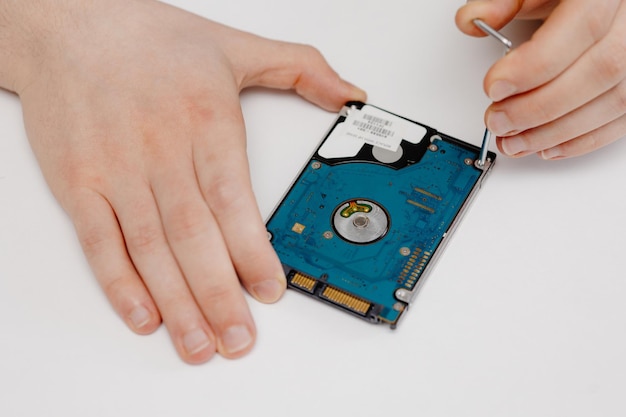 Un homme répare un disque dur sur un fond blanc