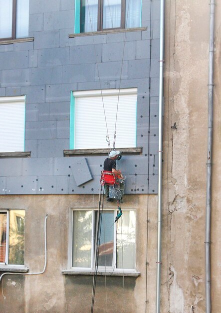 Un homme répare le mur extérieur.