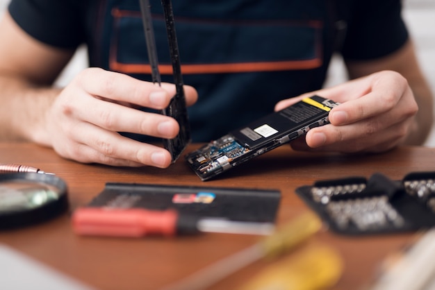 Un homme répare un téléphone portable au travail