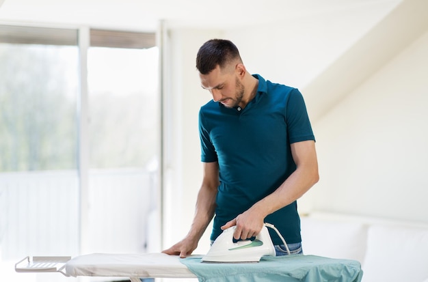 homme repassant la chemise par le fer à la maison