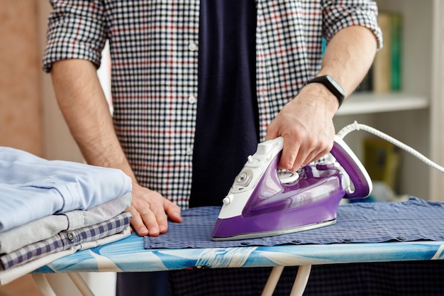 Un Homme Repasse Une Chemise Sur Une Planche à Repasser Avec Un