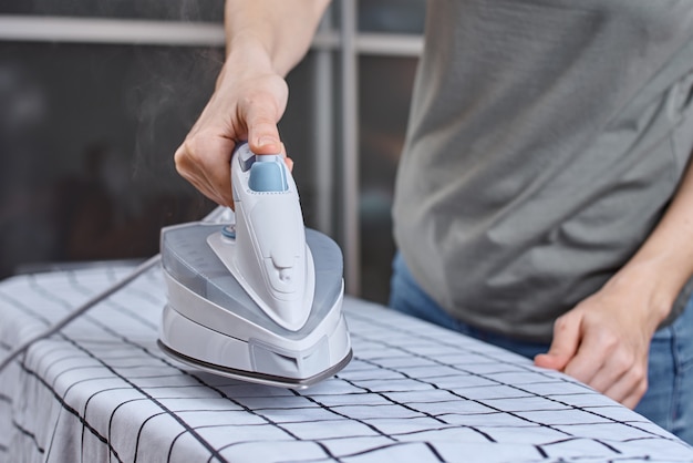 Homme, repasser les vêtements sur une planche à repasser avec un fer moderne