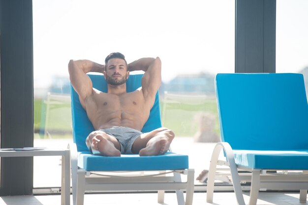 Homme reposant sur des chaises longues au bord de la piscine