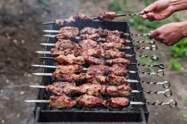 L'homme retourne, cuisine le kebab sur le gril, à l'extérieur