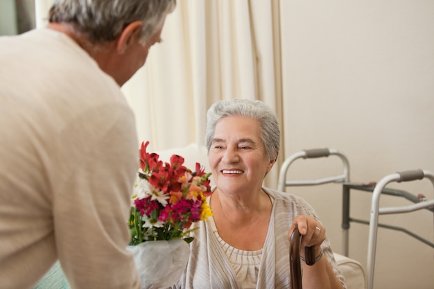 Homme à la retraite offrant des fleurs à sa femme