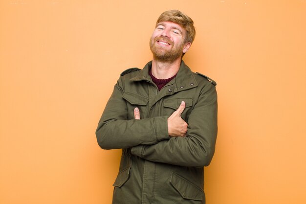 Homme riant joyeusement avec les bras croisés, avec une pose détendue, positive et satisfaite