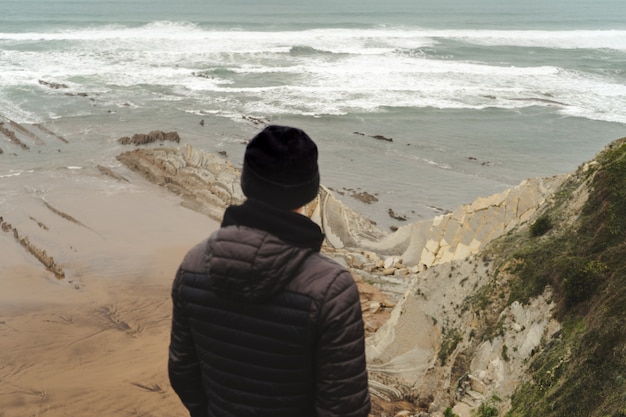 Homme sur le rivage nuageux regardant la mer sur l'herbe