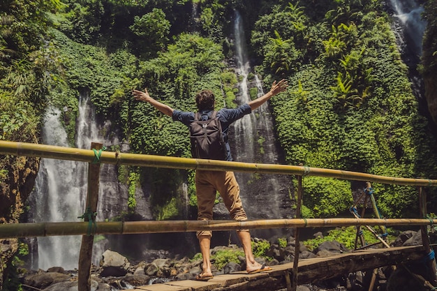 Homme en robe turquoise aux cascades de Sekumpul dans la jungle de l'île de Bali Indonésie Bali Travel Concept