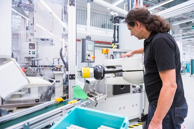 Homme avec robot d'assemblage en usine