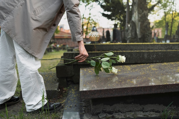 Photo homme avec des roses blanches au cimetière à côté de la tombe