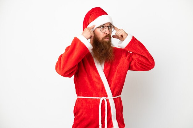 Homme rougeâtre déguisé en Père Noël isolé sur blanc ayant des doutes et pensant