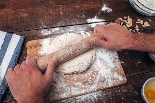 Homme, rouler la pâte sur une planche à découper