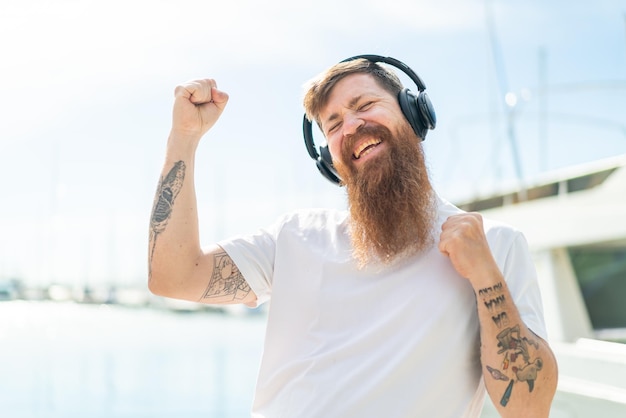 Homme rousse avec barbe écoutant de la musique et dansant