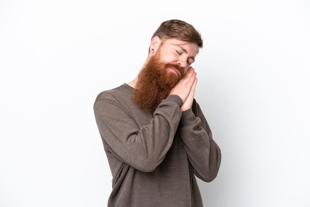 Homme rousse avec barbe isolé sur fond blanc faisant un geste de sommeil dans une expression dorable